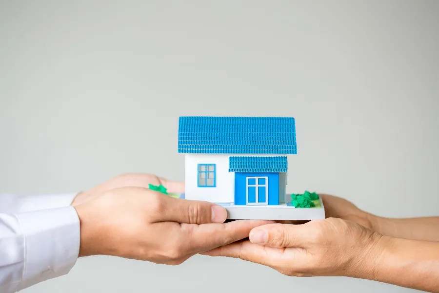 duas pessoas segurando uma miniatura de casa para representar as alternativas de construir e comprar