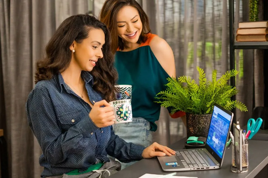 Duas mulheres olham para tela de computador para fechar contrato de compra e venda de terreno